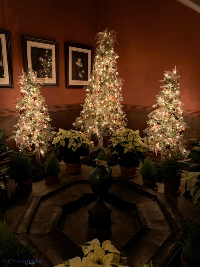 A christmas tree in a living room filled with furniture and vase of flowers