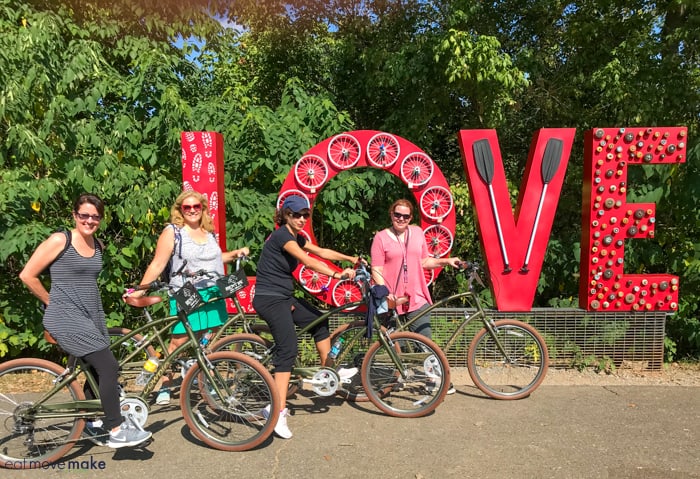 A group of people riding on bicycles by love sign