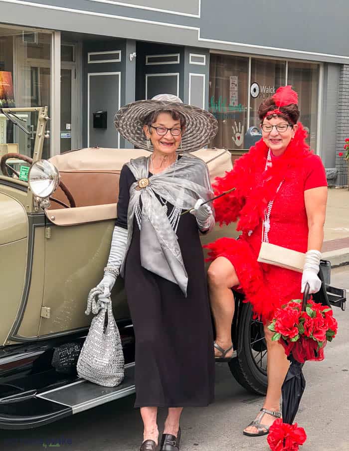 women standing by old-fashioned car