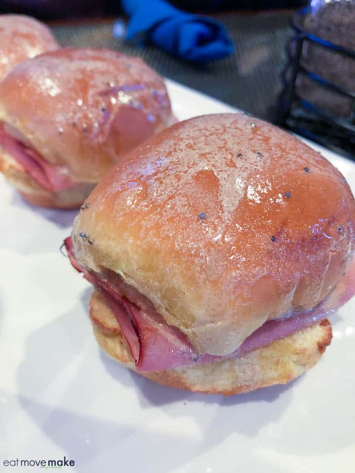 A close up of a sandwich on a plate, with Ham and Slider