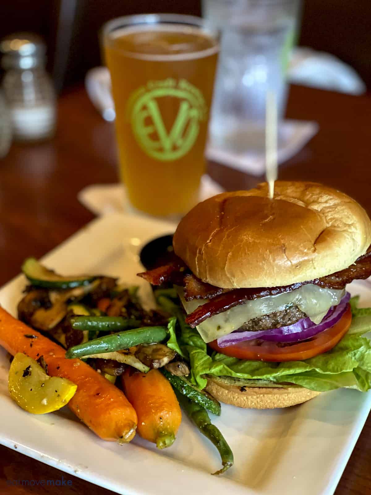 hamburger and veggies on plate with beer in background