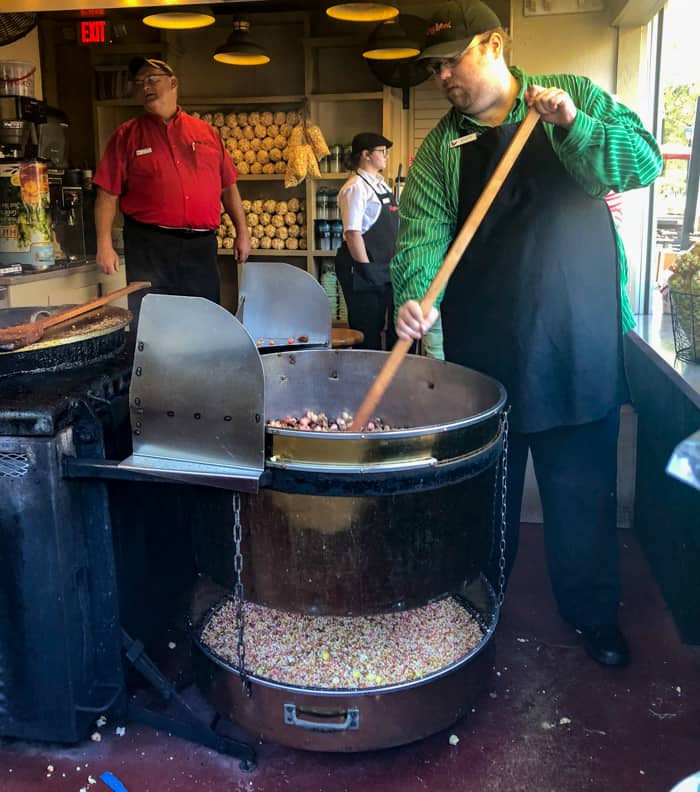 A person cooking kettle corn in a pan 