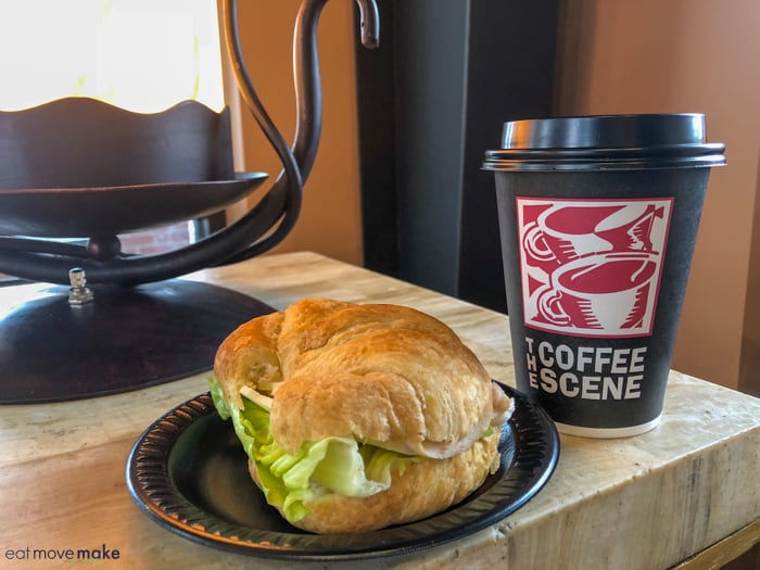 A sandwich sitting on top of a table next to a cup of coffee