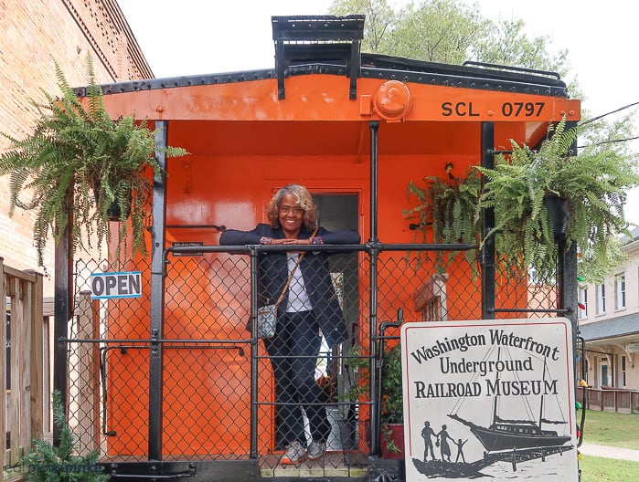 An orange sign that is standing in front of an orange caboose