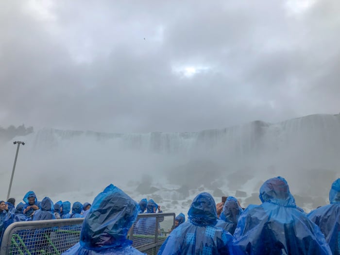 A group of people riding on a boat by the waterfall