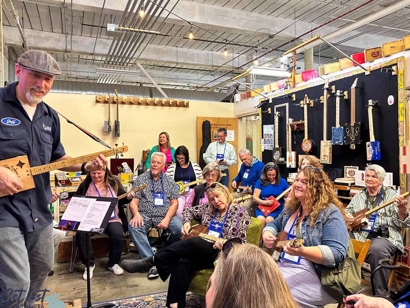 man teaching group how to play cigar box guitars