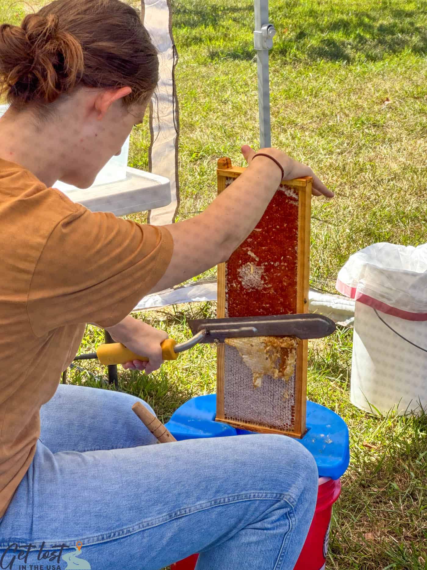 lady using hot knife to uncap honeycombs.