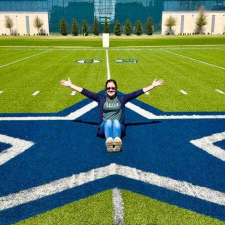 lady sitting on star at Dallas Cowboys practice field.