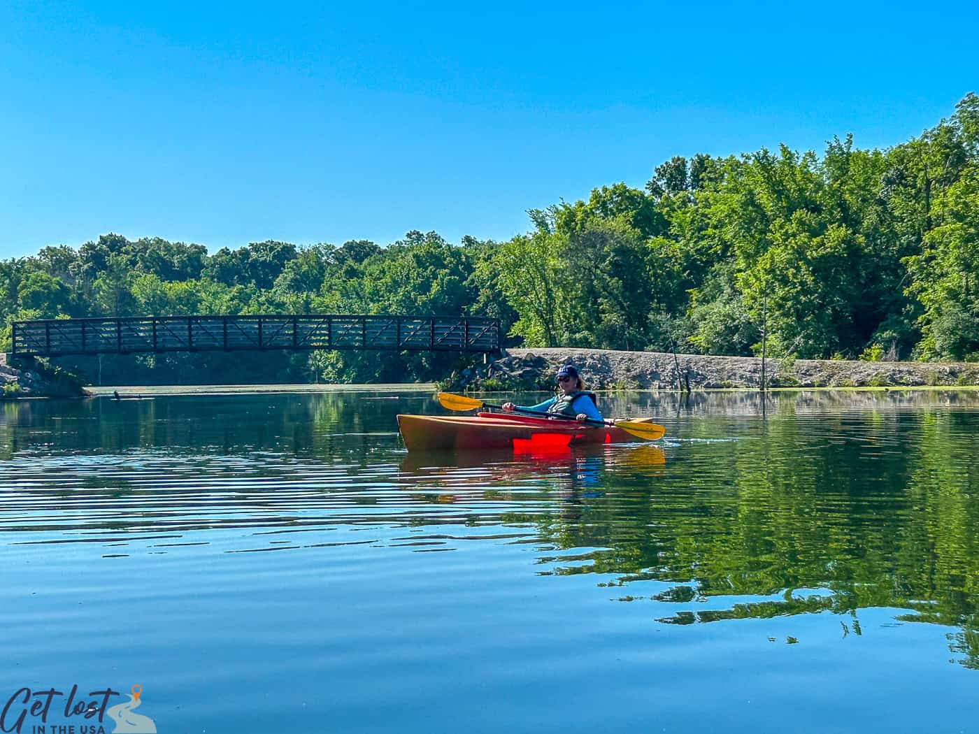 lady kayaking at Brushy Creek with bridge in background.