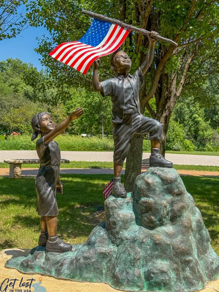 sculpture of two kids proudly raising flag.