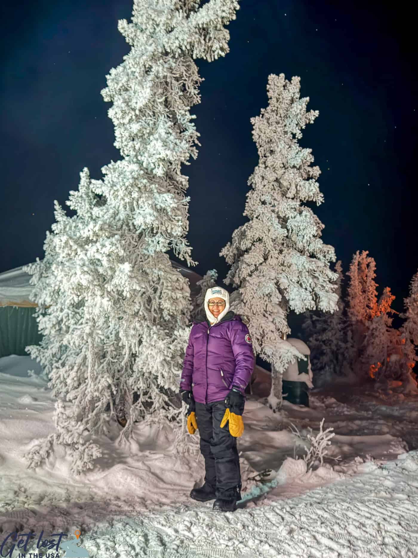 lady standing by icy trees.