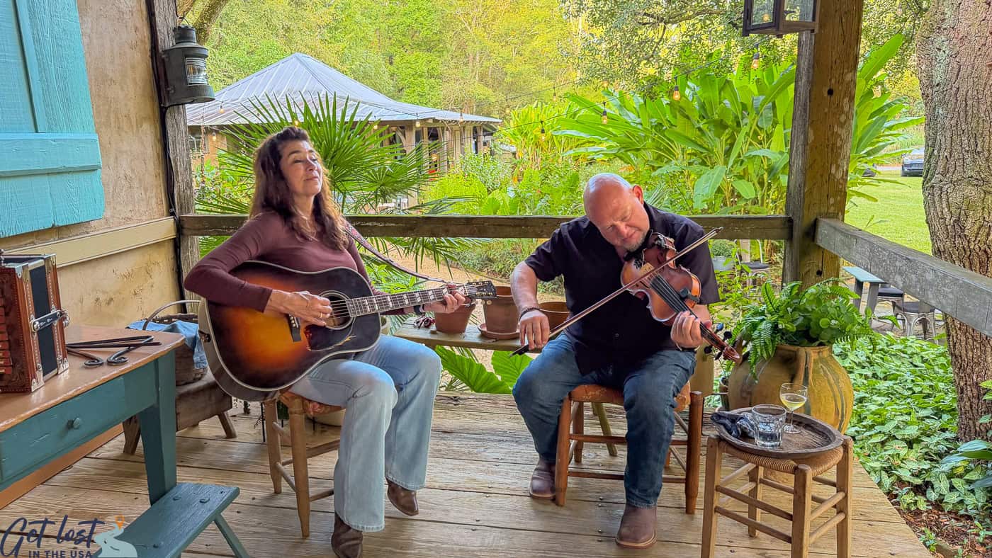 musicians singing and playing fiddle on porch.